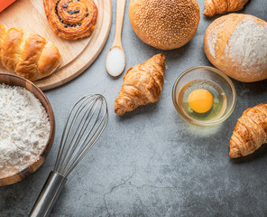 Freshly baked bread on wooden table,Bakery Concept- gold rustic crusty loaves of bread and buns on black chalkboard background. captured from above (top view, flat lay. Layout with copy space.