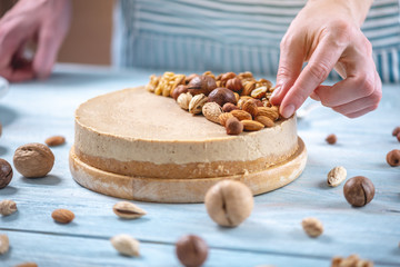 Nutty caramel cheesecake with topping of walnut, almond, hazelnut and macadamia on a wooden...