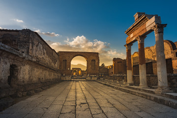 Ruins of ancient city of Pompeii, ancient roman city against Vesuvius volcano at sunset, Italy. Street in Pompeii