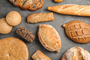 Different kinds of fresh bread on grey table, flat lay