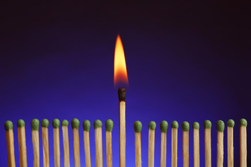 Burning match among others on color background. Difference and uniqueness concept