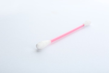 Pink plastic cotton swab on white background