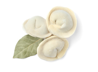 Frozen raw dumplings with bay leaf on white background, top view