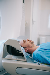 handsome man lying on ct scanner bed during tomography diagnostics in hospital