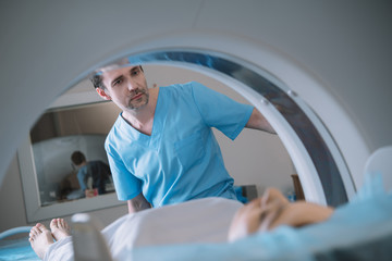 selective focus of attentive radiologist operating computer tomography scanner during patients...
