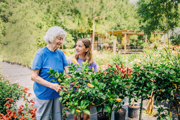 Grandmother and Granddaughter Spending time together and bonding outside looking and shopping for flowers outdoors 