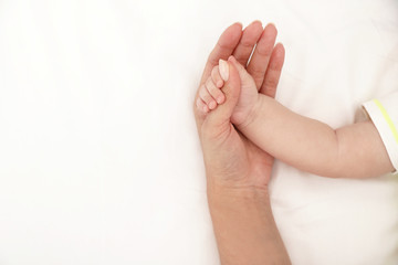 Mother holding her baby's hand on bed, top view. Space for text