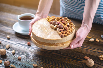 Raw nutty cake decorated with walnut, almond, hazelnut on a dark wooden background. Gluten free and sugar free food