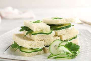 Tasty cucumber sandwiches with parsley on plate, closeup