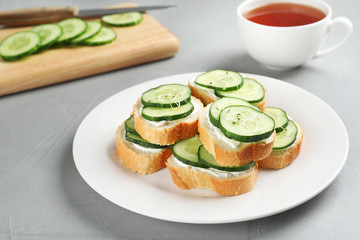 Plate with traditional English cucumber sandwiches on table