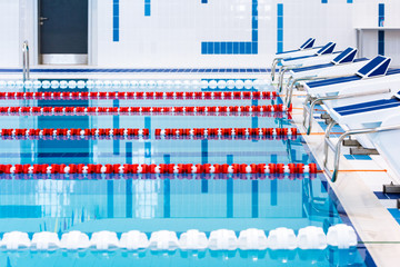 Swimming pool with marked red and white lanes. Empty swimming pool without people with quiet standing water. Water sports in indoor pool.