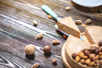 Raw nutty cake decorated with walnut, almond, hazelnut on a dark wooden background. Healthy fresh...