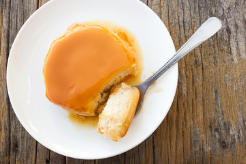 Homemade caramel custard cake on white plate. Spoon cutting caramel cake.