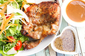 Homemade black pepper pork chop steak with salad on white plate.