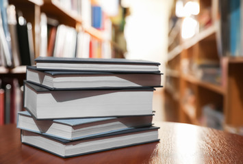 Stack of books on table in library. Space for text