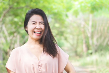 happy beautiful Asian woman laughing outdoor with green nature background 