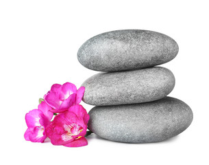 Stack of spa stones and beautiful flowers on white background