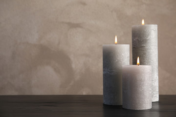 Burning candles on table against color background. Space for text