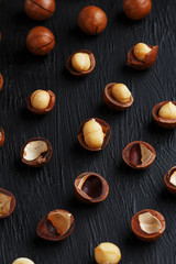 Purified and shell repeats macadamia nuts on black textural stone background. Healthy eating concept