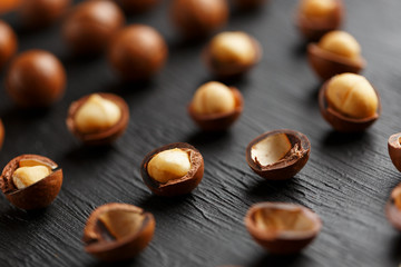 Purified and shell repeats macadamia nuts on black textural stone background. Healthy eating concept