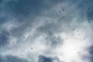 Raindrops on the windshield; in the bright light managing to break through dark, storm clouds, California