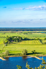 View over the Elbauen in Lower Saxony, Germany. You see a landscape with fields, meadows and the river Elbe under a blue sky with white clouds.