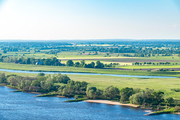 Obraz premium View over the Elbauen in Lower Saxony, Germany. You see a landscape with fields, meadows and the river Elbe.