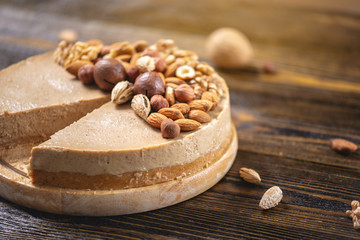 Fototapeta na wymiar Raw nutty cake decorated with walnut, almond, hazelnut on a dark wooden background. Gluten free and sugar free product