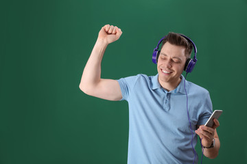 Man in headphones with mobile device on color background. Space for text