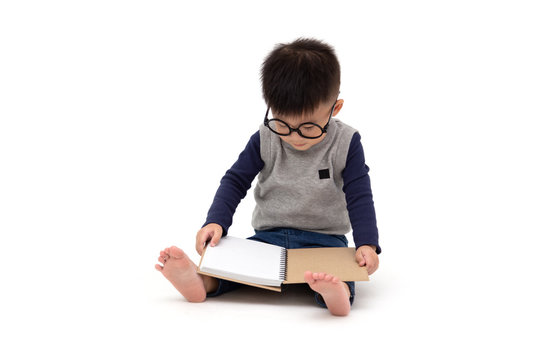 Portrait of a cute Asian little boy wearing glasses and reading a book isolated over white background