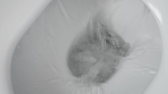 White toilet bowl in a bathroom. Flush water away