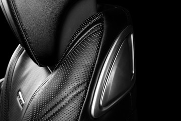 Black leather interior of the luxury modern car. Perforated leather comfortable seats with stitching isolated on black background. Modern car interior details. Car detailing. Black and white