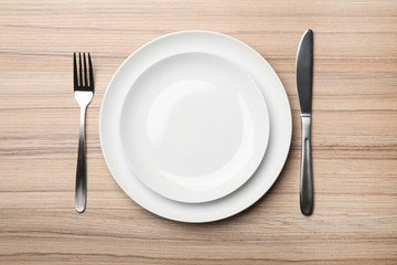 Stylish ceramic plates and cutlery on wooden background, flat lay