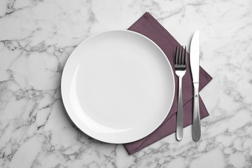 Stylish ceramic plate, napkin and cutlery on marble background, flat lay