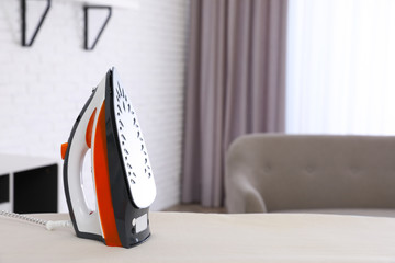 Modern electric iron on board indoors. Space for text
