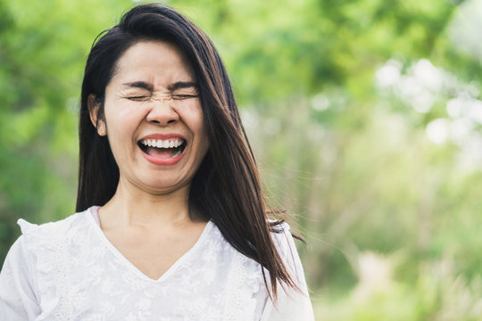 happy Asian woman laughing outdoor with green park nature background 