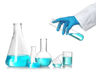 Scientist holding test tube over table with laboratory glassware against white background. Chemical...