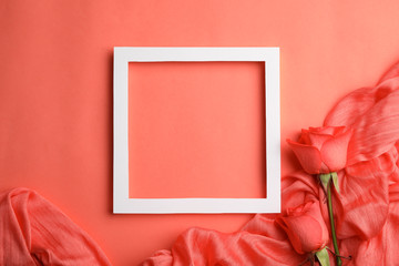 Flat lay composition with frame, roses and fabric on coral background. Space for text