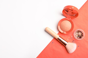 Flat lay composition with coral blush, glitter and makeup brush on color background. Space for text
