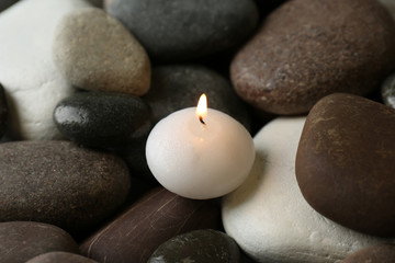 Obraz na płótnie Canvas Small burning candle on beautiful spa stones