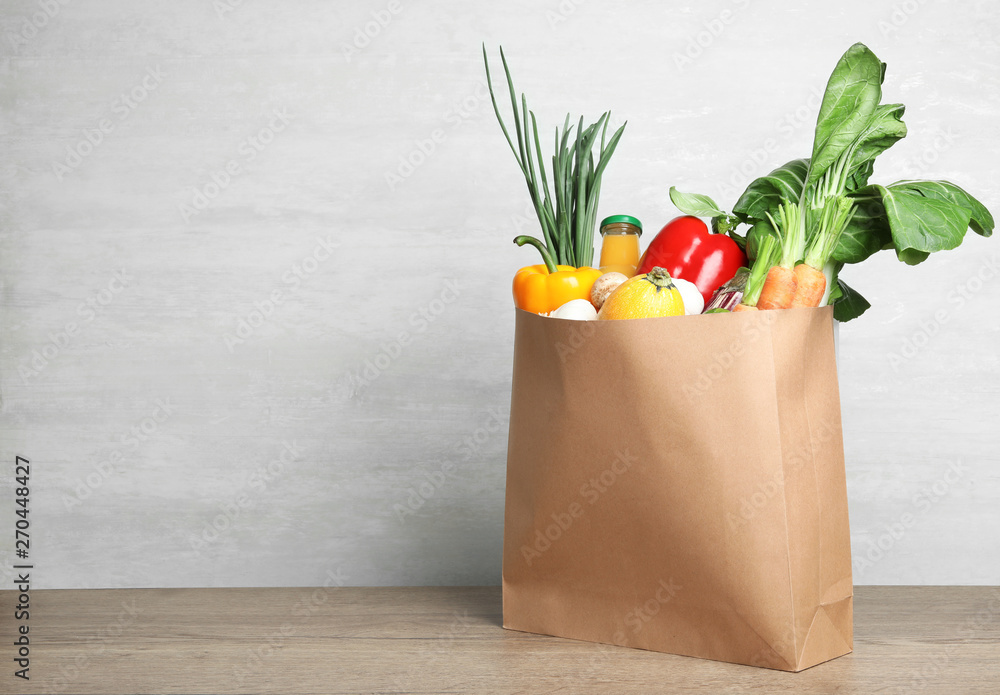 Poster Paper bag with vegetables and bottle of juice on table against grey background. Space for text