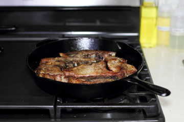 Country style cut pork ribs in a cast iron pan on the stove top.