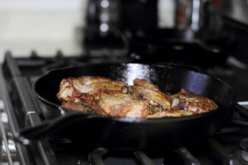 Country style cut pork ribs in a cast iron pan on the stove top.