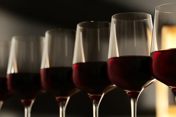 Glasses of red wine against blurred background, closeup. Expensive drink