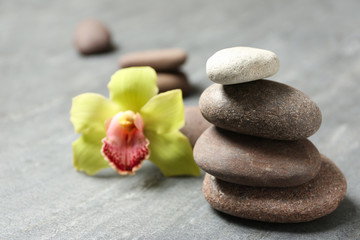 Fototapeta na wymiar Stacked spa stones with flower on grey table. Space for text