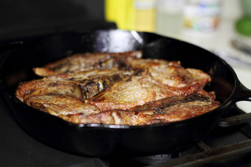 Country style cut pork ribs in a cast iron pan on the stove top.