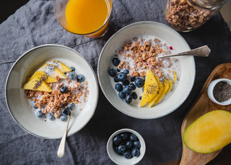 Top view of breakfast table  for two persons, crunchy granola with fresh berries and cream or milk. Flat lay, healthy eating.