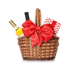 Festive basket with bottles of wine and gift on white background