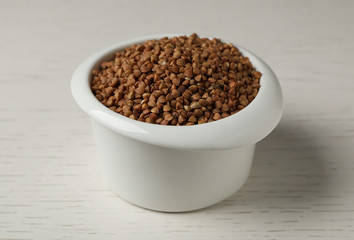 Uncooked buckwheat in ceramic bowl on table