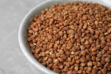 Uncooked buckwheat in bowl on table, closeup